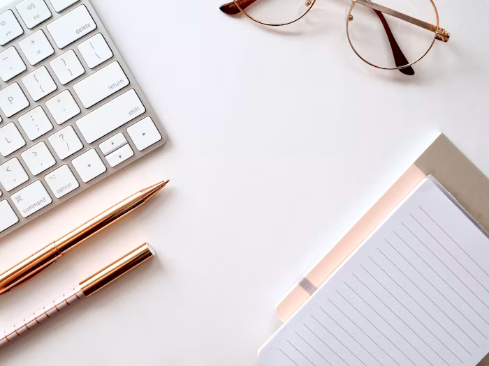 A pen resting near lined paper and a pair of eyeglasses
