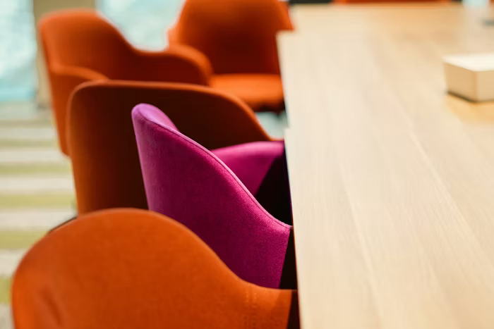 Orange and pink chairs arranged around a wooden meeting table