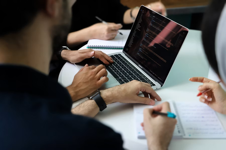 A small group gathered around a laptop discussing a strategy