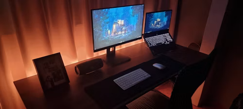 A desk holding both a desktop computer and a laptop