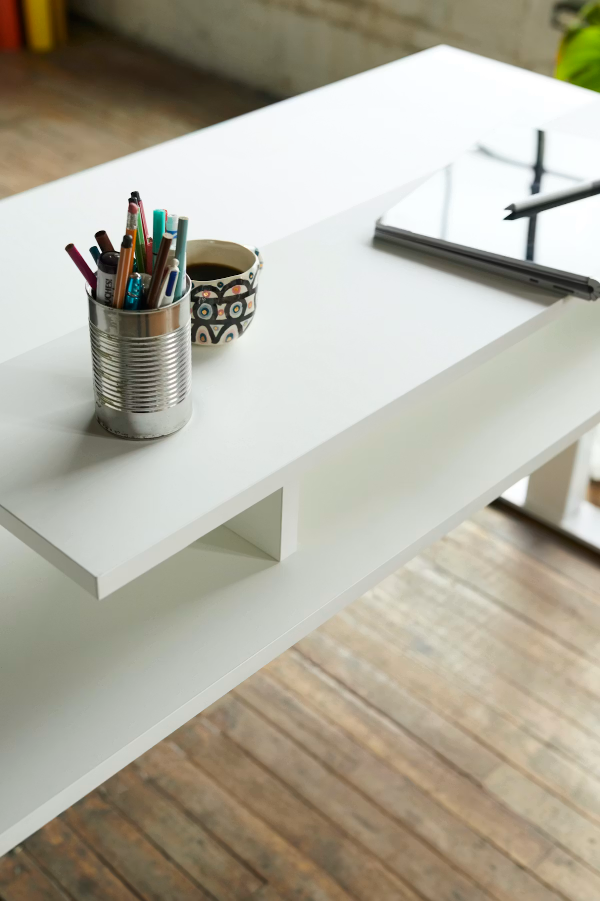 Pencils standing neatly inside a white steel cup on a light wooden table