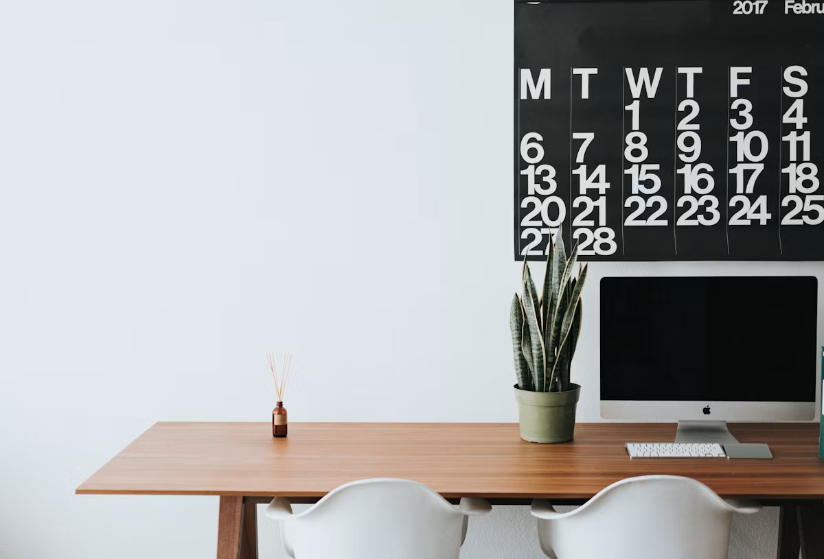 A silver desktop monitor sitting on a warm brown wooden desk
