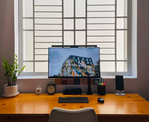 A black flat-screen monitor on a brown wooden desk