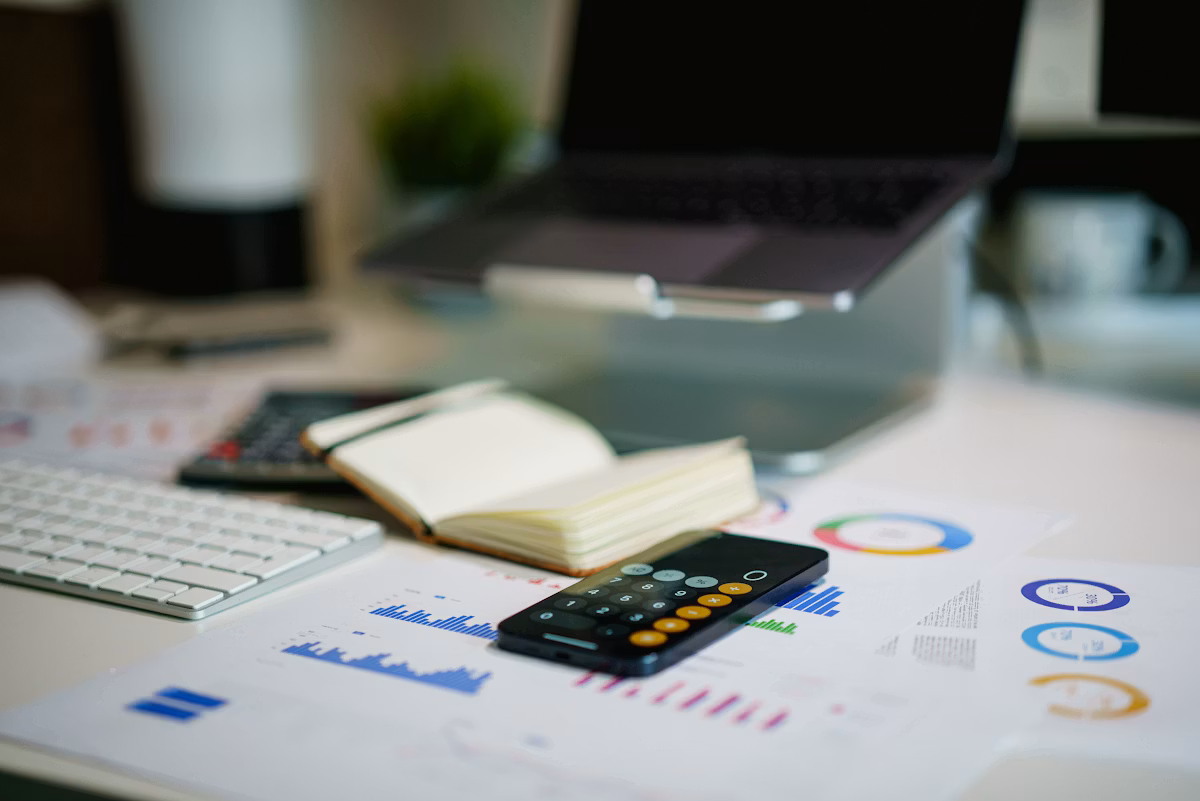 A desk holding a smartphone displaying financial charts