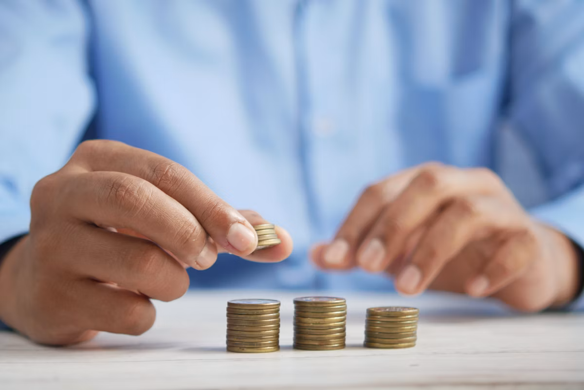 A person carefully stacking coins on top of a table